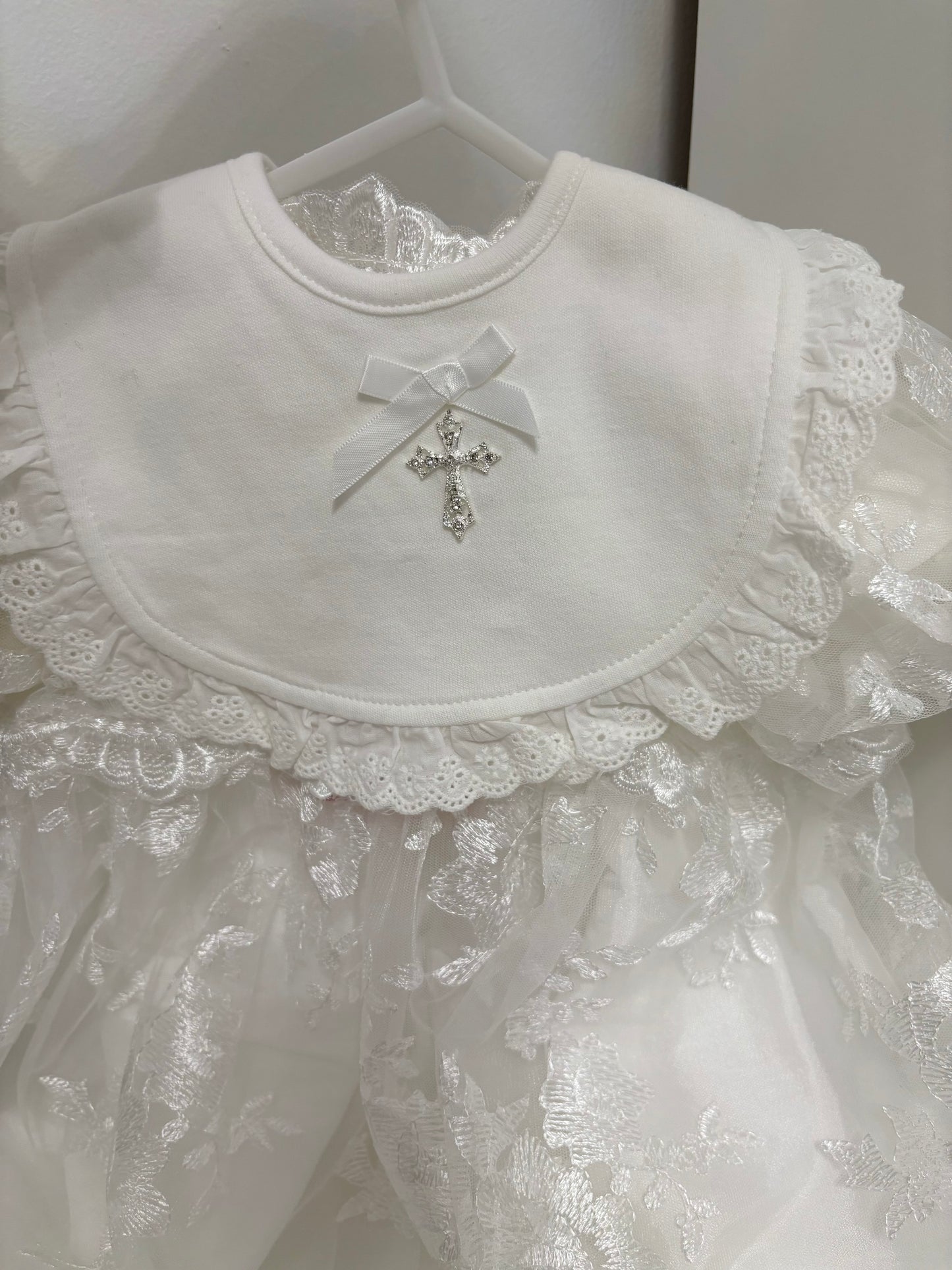 Ivory baby's bid with brodiere anglaise trim, bow with single pearl and chrystal cross.