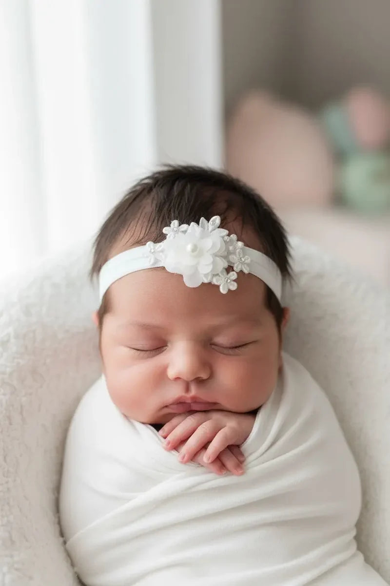 Newborn baby wearing an elegant off-white floral headband for christening